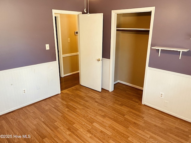 unfurnished bedroom featuring a closet, wainscoting, and wood finished floors