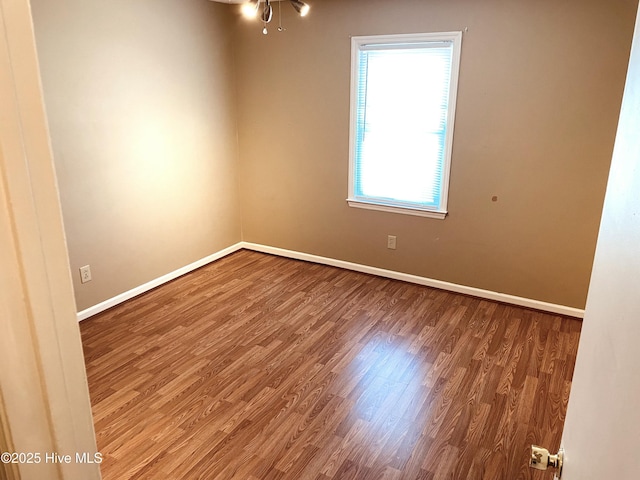 spare room featuring baseboards and wood finished floors