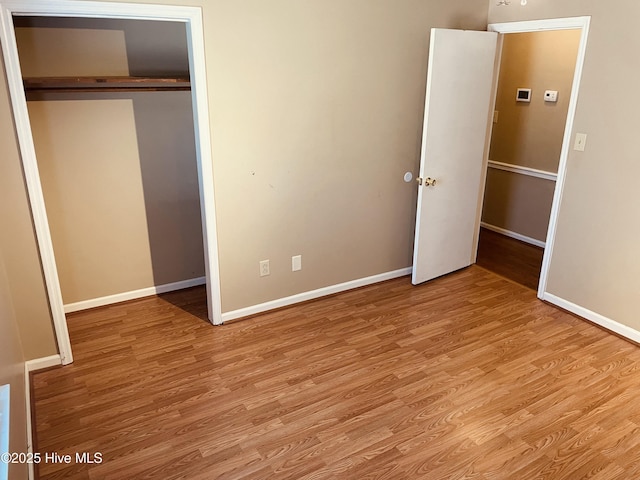 unfurnished bedroom with a closet, baseboards, and wood finished floors