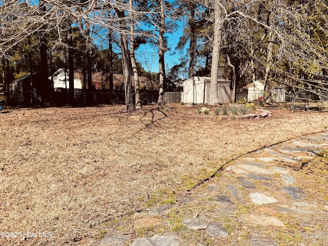 view of yard with a fenced backyard, a storage unit, and an outdoor structure