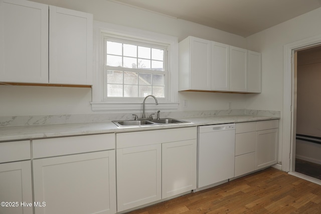 kitchen featuring white dishwasher, wood finished floors, a sink, white cabinets, and light countertops