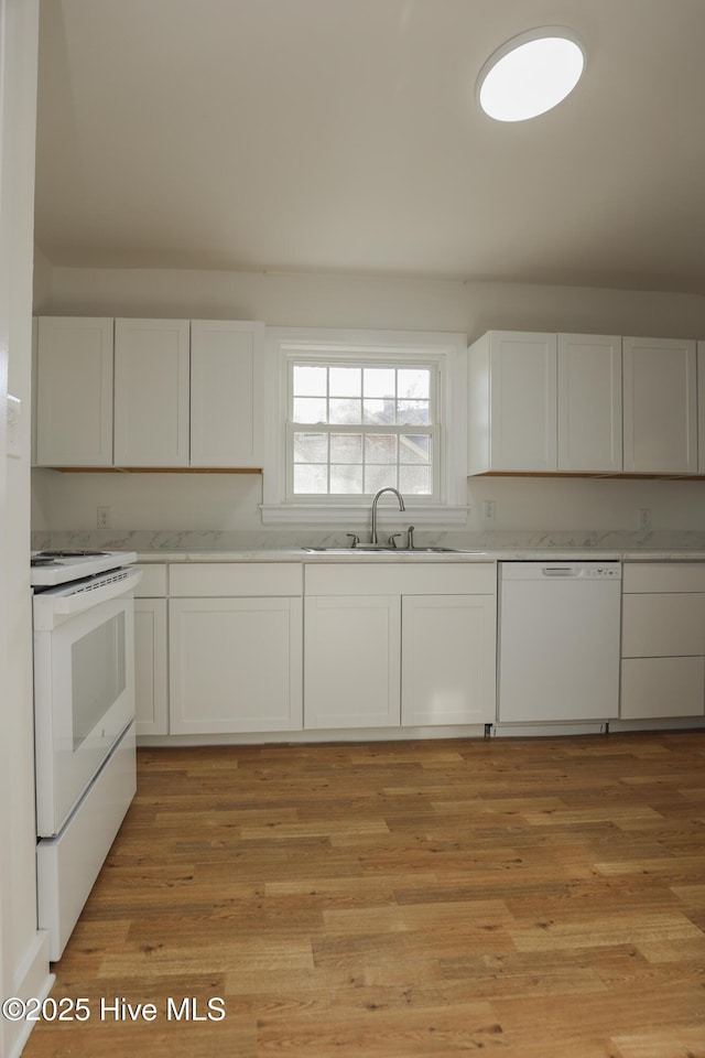 kitchen with light wood-type flooring, white appliances, white cabinets, and a sink