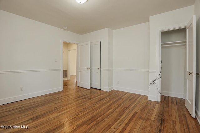 unfurnished bedroom with a closet, wood finished floors, and baseboards