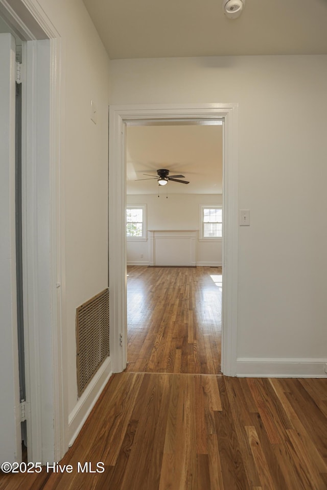 hallway with baseboards, visible vents, and dark wood finished floors