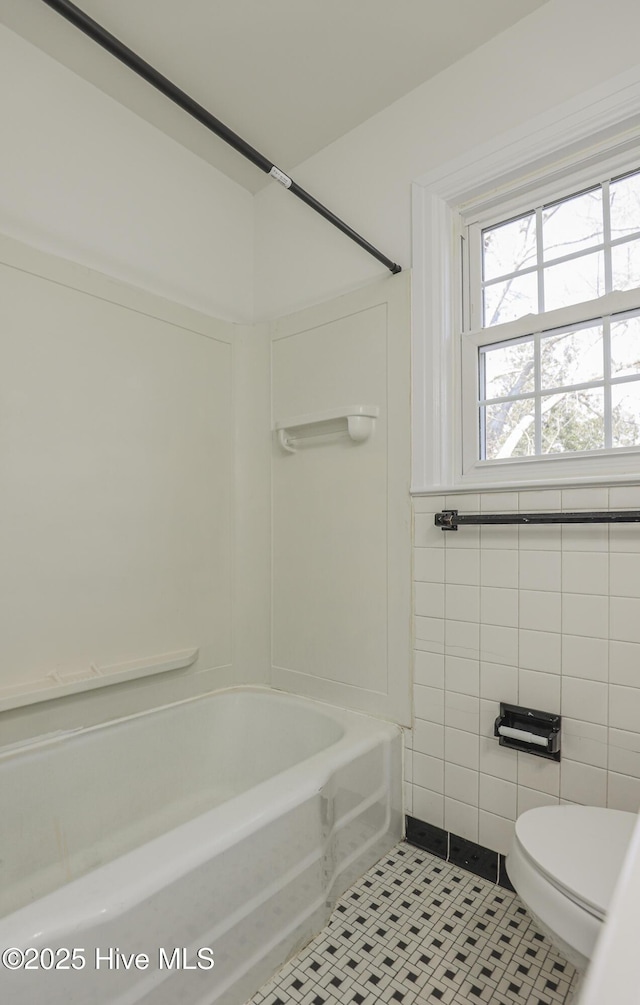 full bath with toilet, bathtub / shower combination, tile walls, and tile patterned floors