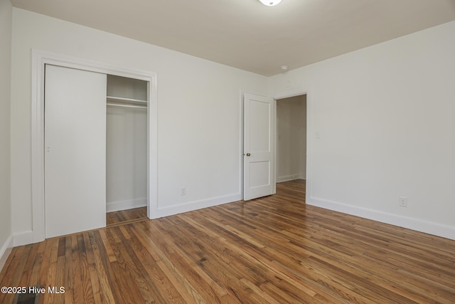 unfurnished bedroom featuring a closet, baseboards, and wood finished floors