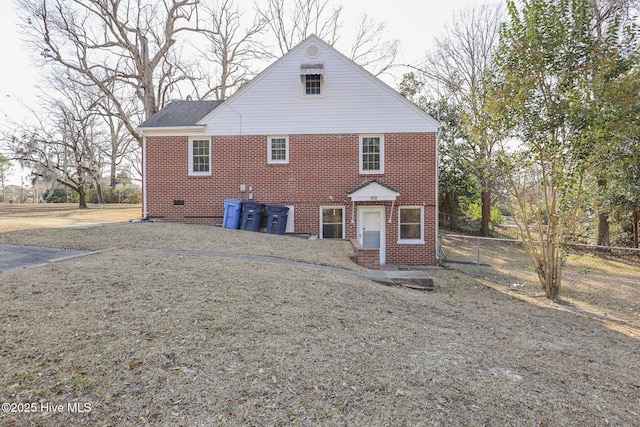 rear view of house featuring brick siding and fence