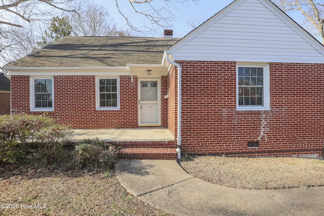 view of front of property with roof with shingles, brick siding, and a chimney