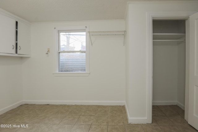 interior space featuring a closet, light tile patterned flooring, a textured ceiling, and baseboards