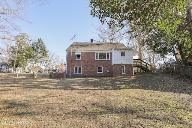 back of house with a yard, brick siding, fence, and stairway