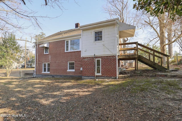 back of property with stairway, brick siding, and a chimney