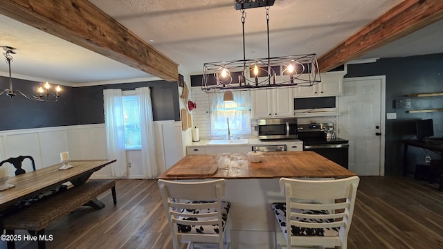 kitchen featuring electric range, stainless steel microwave, beam ceiling, and wainscoting