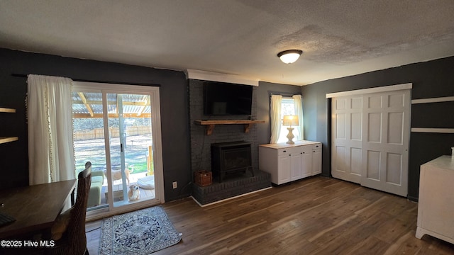 living area with a brick fireplace, a textured ceiling, and dark wood-style flooring