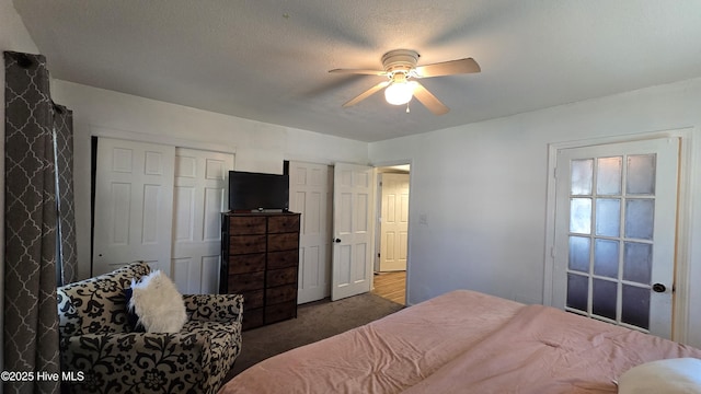 bedroom with a ceiling fan, dark colored carpet, and two closets