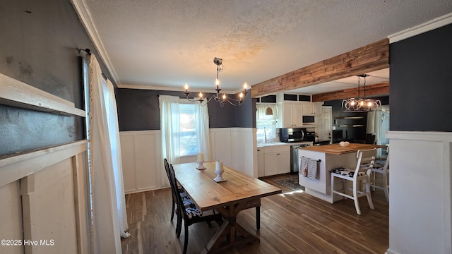 dining space with a wainscoted wall, a textured ceiling, dark wood-style floors, and an inviting chandelier