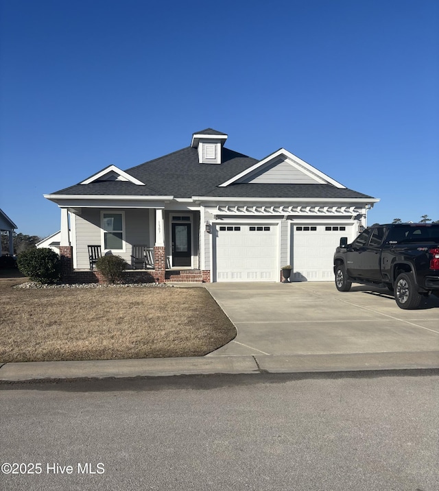 view of front of house with a porch, driveway, a shingled roof, and a garage