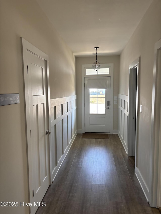 doorway featuring dark wood-style flooring and baseboards