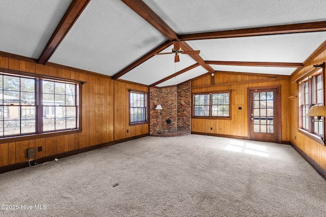 unfurnished living room with a textured ceiling, vaulted ceiling with beams, wooden walls, baseboards, and carpet