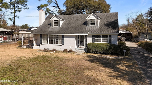 cape cod home with a shingled roof, a chimney, a front lawn, and brick siding