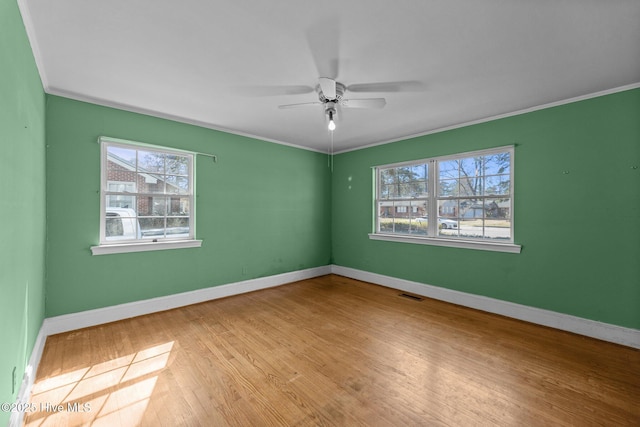 spare room featuring baseboards, visible vents, wood finished floors, and ornamental molding