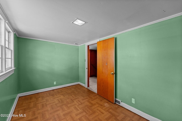 empty room featuring crown molding and baseboards