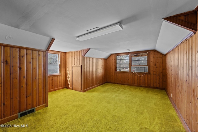 additional living space with carpet floors, visible vents, vaulted ceiling, wooden walls, and cooling unit