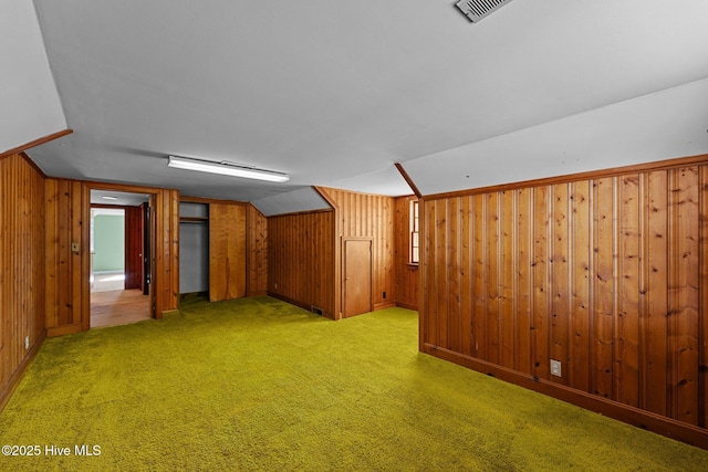 finished below grade area featuring visible vents, light colored carpet, and wooden walls