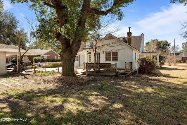 rear view of property featuring a chimney and a wooden deck