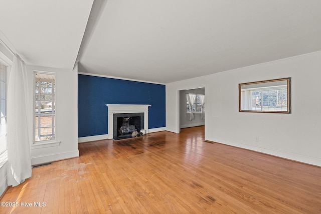 unfurnished living room featuring wood-type flooring, visible vents, a fireplace, and baseboards