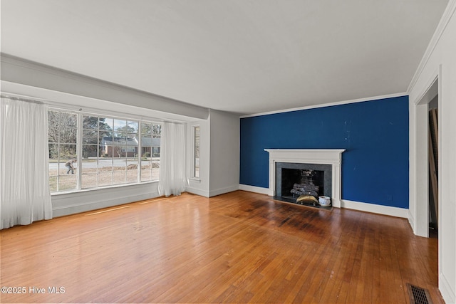 unfurnished living room featuring ornamental molding, hardwood / wood-style floors, visible vents, and baseboards