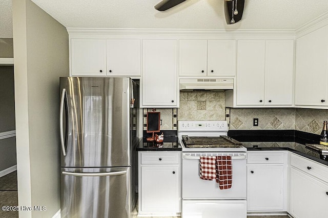 kitchen with dark countertops, under cabinet range hood, white gas range oven, and freestanding refrigerator