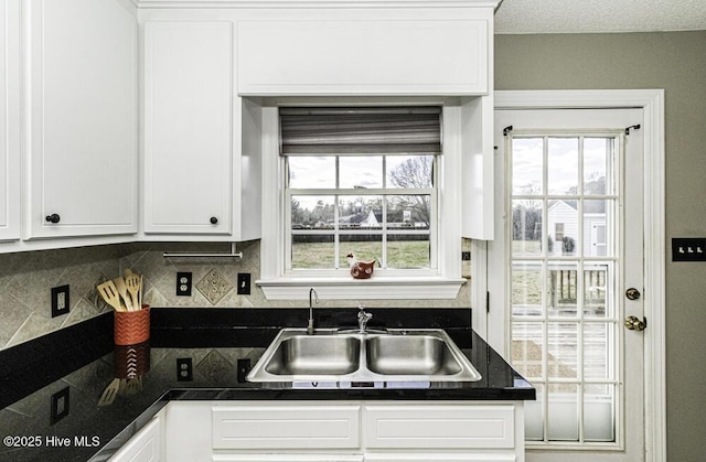 kitchen featuring a healthy amount of sunlight, white cabinets, and a sink