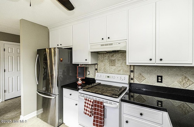 kitchen with under cabinet range hood, freestanding refrigerator, white stove, tasteful backsplash, and dark countertops