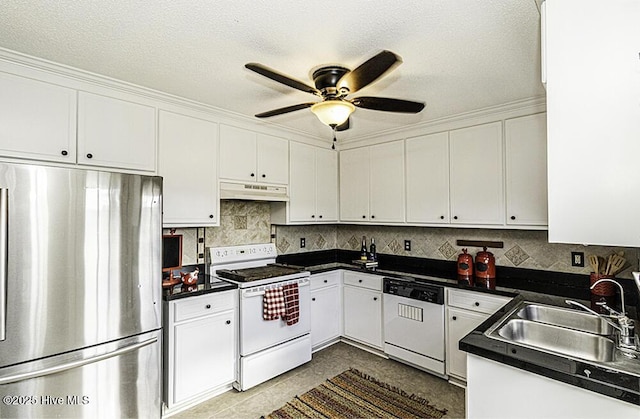 kitchen with dark countertops, white cabinets, a sink, white appliances, and under cabinet range hood