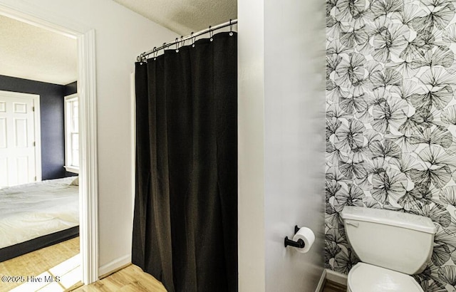 bathroom featuring toilet, a textured ceiling, baseboards, and wood finished floors