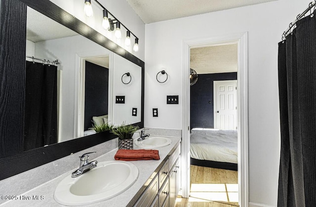 ensuite bathroom with a sink, a textured ceiling, ensuite bathroom, and double vanity