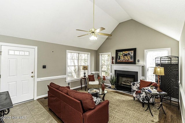 tiled living area with lofted ceiling, ceiling fan, a fireplace, and baseboards