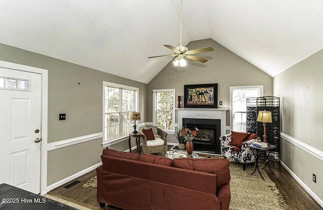 living room featuring lofted ceiling, a fireplace, wood finished floors, visible vents, and a ceiling fan