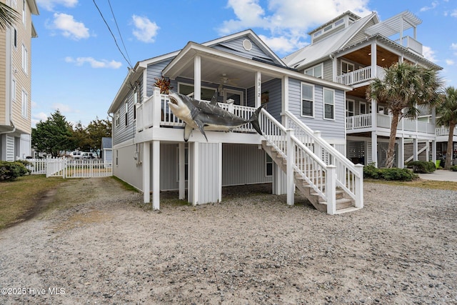 view of front of home featuring stairway, a ceiling fan, fence, and driveway