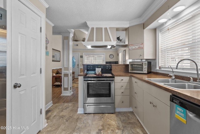 kitchen featuring crown molding, a toaster, appliances with stainless steel finishes, white cabinets, and a sink