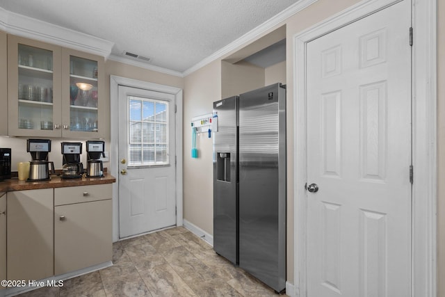 kitchen featuring visible vents, a textured ceiling, stainless steel fridge with ice dispenser, crown molding, and glass insert cabinets