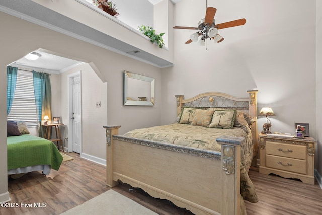 bedroom featuring baseboards, wood finished floors, arched walkways, and ornamental molding