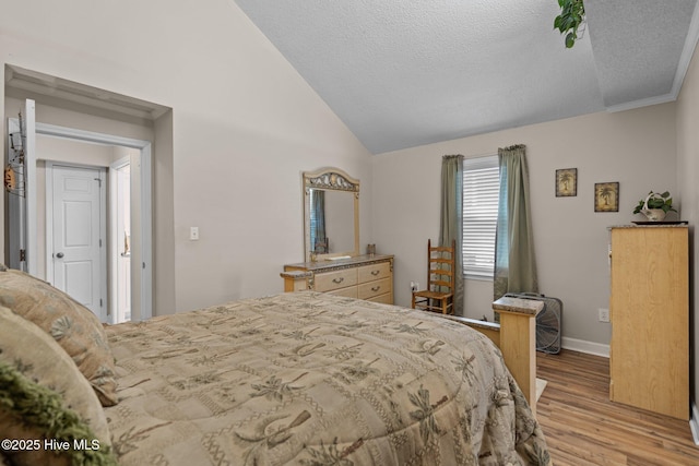 bedroom with vaulted ceiling, light wood-style flooring, baseboards, and a textured ceiling