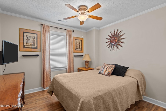 bedroom with visible vents, baseboards, a textured ceiling, and wood finished floors