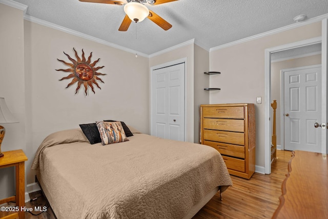 bedroom featuring a closet, a textured ceiling, wood finished floors, and crown molding