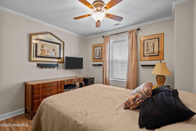 bedroom with visible vents, a textured ceiling, wood finished floors, and ornamental molding