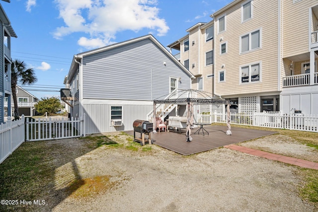 back of property with a gazebo, a wooden deck, and fence