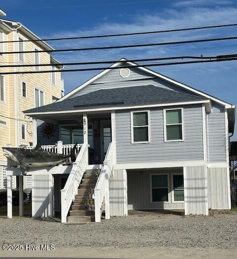 raised beach house with stairway and a porch