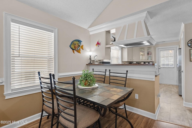 dining area with vaulted ceiling, baseboards, and a textured ceiling