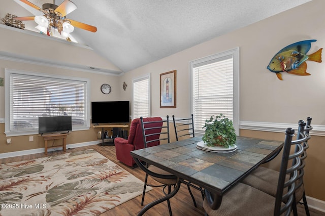 dining room with a wealth of natural light, baseboards, lofted ceiling, and wood finished floors